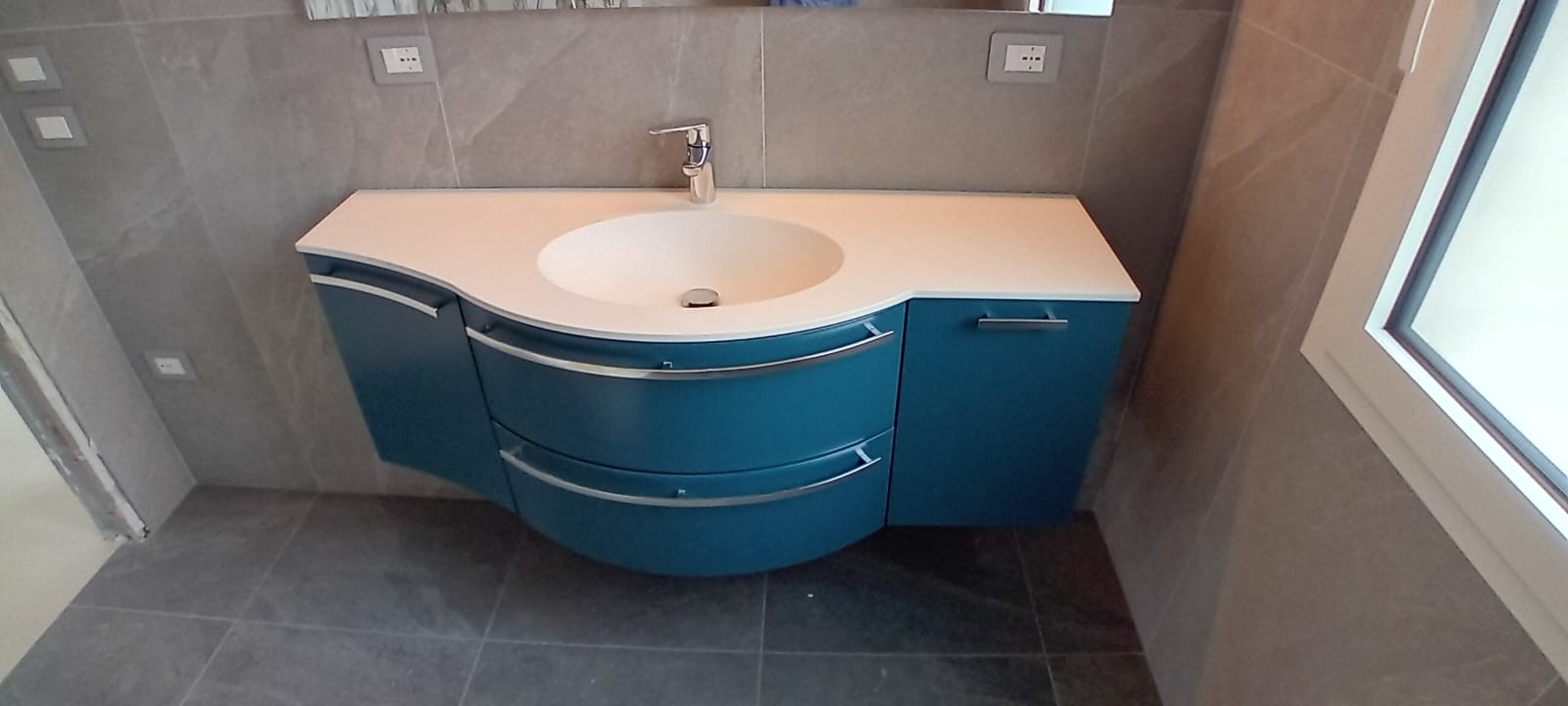Mobile bagno curvo Compab laccato lucido installato presso un nostro cliente, con lavabo integrato e specchiera.